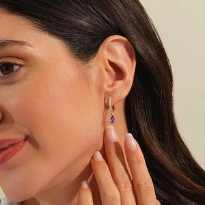 Detail of purple teardrop gemstone earrings with gold plating on a female model