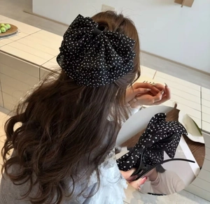 Vue détaillée d'une pince à cheveux vintage à pois avec nœud sur de longs cheveux ondulés