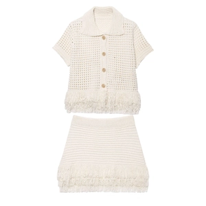 Two-piece knit set featuring ivory short sleeve top and mini skirt with fringe hem details
