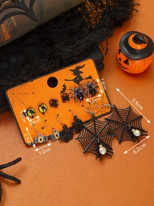 Detailed view of Halloween earring set with black spider webs and BOO charms on orange background