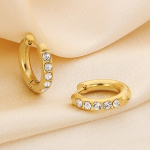Detail view of gold U-shaped stainless steel earrings with rhinestones on silk