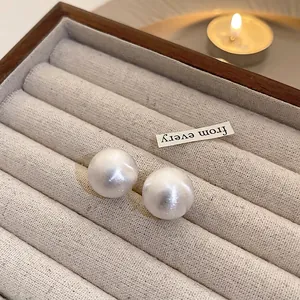 Close-up of elegant white acrylic pearl stud earrings placed in a beige velvet jewelry box