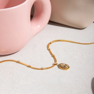 Vintage stainless steel gold portrait pendant necklace with zircon on a textured surface