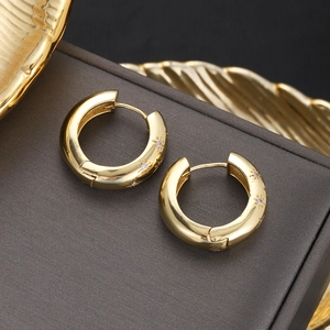 Macro detail of 18K gold-plated star-engraved hoop earrings with micro-inlaid zircons