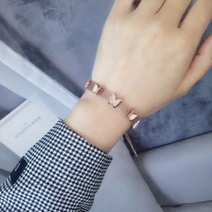 Gros plan d'un bracelet papillon en maille or rose porté au poignet pour femme