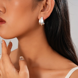Détail macro de boucles d'oreilles argentées plissées en goutte sur le modèle