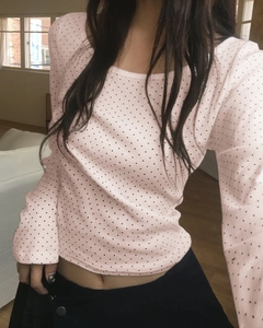 Détail du t-shirt court rose à manches longues avec pois noirs et col rond élégant