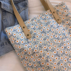 Détail du sac cabas floral avec imprimé marguerites, anses en cuir et rivets en bronze
