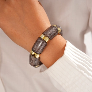 Detail of dark gray acrylic beads with gold spacers on wrist with white shirt sleeve