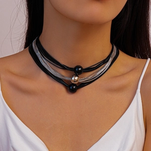 Detail of layered necklace featuring black woven rope, silver chains and sphere pendants