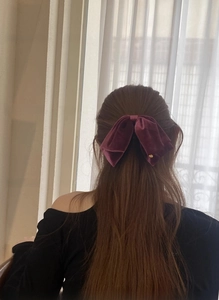 Detail einer eleganten lila Samt-Haarklammer mit Schleife an langem Haar von hinten