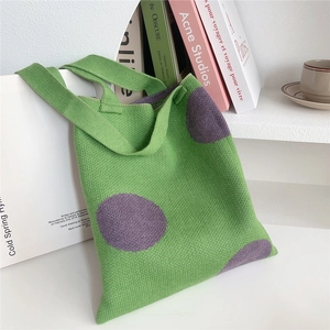 Dettaglio della borsa in maglia verde a pois viola su una base bianca