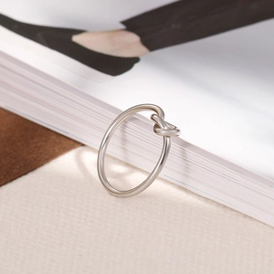 Detail of silver knot ring showing sleek metallic texture against a book background