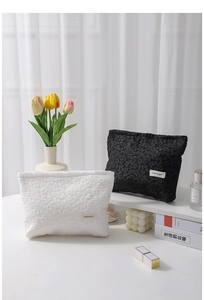 Detail of black and white canvas makeup bags with floral embossed texture and H&R logo
