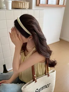 Close-up of a stylish yellow headband paired with a woven summer tote bag and chic outfit
