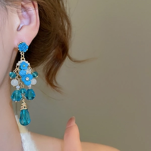 Détail de boucles d'oreilles roses bleues sur mannequin montrant la longueur et l'élégance