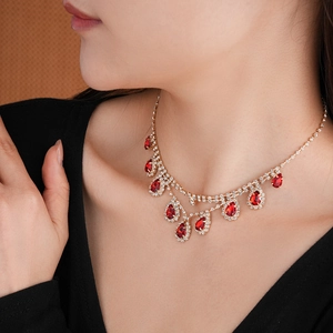 Close-up of luxury gold necklace with red teardrop gem and diamonds on a model