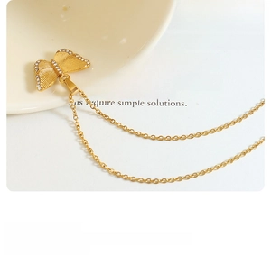 Macro detail of gold butterfly necklace with zircon inlay and brushed metal texture