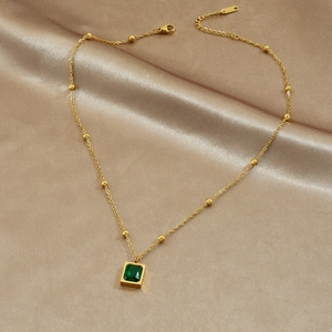 Gold-plated stainless steel necklace with green rectangular gemstone on champagne silk