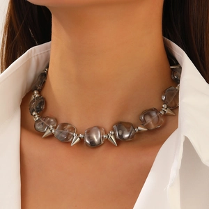 Close-up of punk necklace with irregular smoke grey beads and silver cone pendants on a model