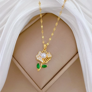 Detail of flower necklace with white pearl, diamond petals, and green leaves in a jewelry box