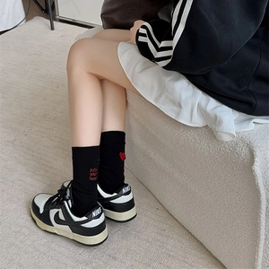 Detail of black cotton socks featuring red heart embroidery and Follow your heart text
