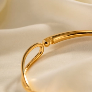 Gros plan du fermoir de bracelet en acier inoxydable doré 18K sur soie beige
