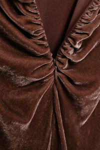 Dettaglio di un abito in velluto marrone con pieghe eleganti e zip invisibile sul retro