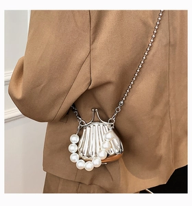 Detail der silbernen Mini-Tasche in Muschelform mit Perlengriff und Metallkette am Model