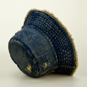 Macro detail of distressed dark blue denim bucket hat with frayed edges and ripped texture