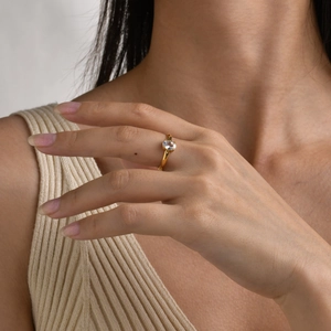 Detail shot of a gold-plated stainless steel ring with a clear oval gemstone on a finger