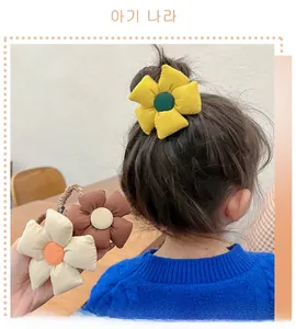 Detail of plush sunflower hair ties showing soft fabric texture and warm colors on a child
