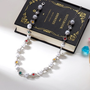 Hip hop pearl and colorful crystal flower necklace displayed on a black vintage book