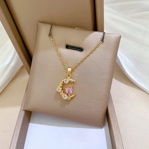 Macro shot of gold moon pendant with pink heart gemstone and zircons in a jewelry box