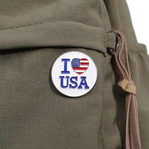 Round metal badge with USA flag heart and I love USA text on a green backpack
