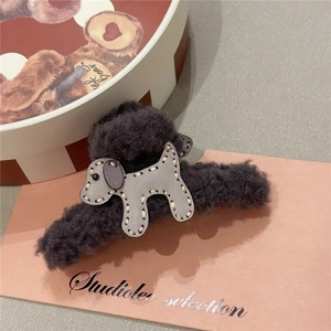 Detail of plush dark grey claw clip featuring a stitched leather dog on pink card