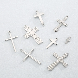 Set of eight polished titanium steel punk cross pendants on a white textured background