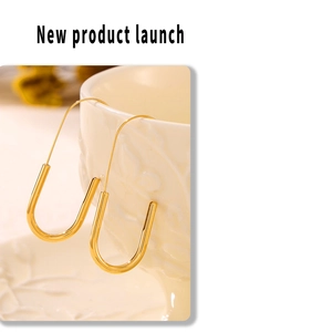 Detail of 18k gold plated paperclip earrings hanging on a white ceramic bowl edge