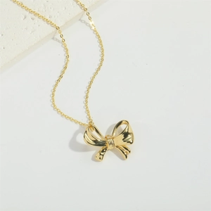 Detailed view of the gold bow necklace featuring a delicate polished metallic pendant