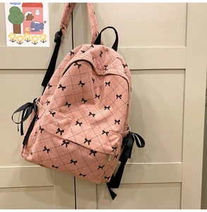 Detailed texture of pink corduroy schoolbag with black ribbon and bow patterns