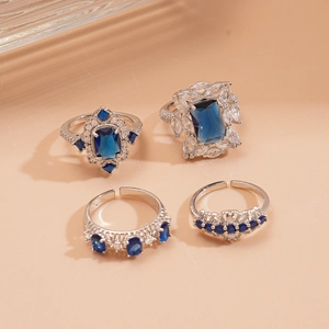 Retro geometric rings with blue zircons in droplet and square shapes on orange surface