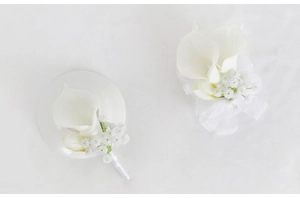 Detail of white calla lily boutonniere and wrist corsage with silk ribbon for weddings