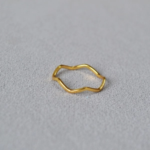 Macro view of minimalist wave-shaped gold-plated brass ring with smooth curved details