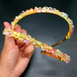 Detail of handmade gold metal headband with colorful irregular raw crystal stones
