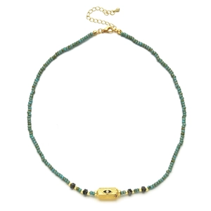 Macro detail of turquoise beads with gold Evil Eye charm and lobster clasp closure
