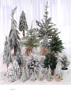 Close-up of mini tabletop Christmas trees with snow flocking and natural wooden bases