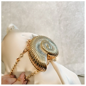 Detailed view of golden conch shell mini bag with metal texture and beaded chain