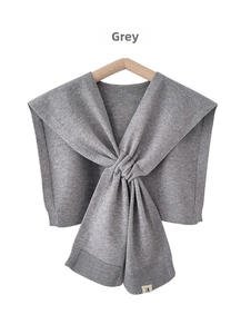 Detail of grey knitted shawl featuring twisted knot design and ribbed texture on hanger
