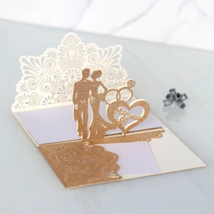 Close-up of 3D laser-cut wedding card featuring a gold glitter LOVE heart and ring detail