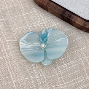 Close-up of blue orchid hair clip with pearl center on rustic linen background